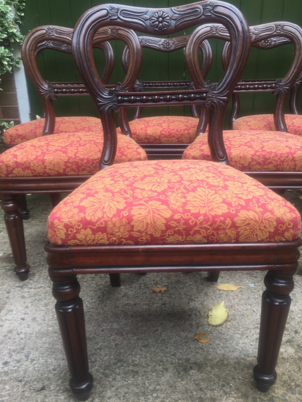 A set of six early nineteenth-century George IV mahogany dining chairs featuring carved balloon back frames, reeded legs, and red pattern upholstered seats. View IV