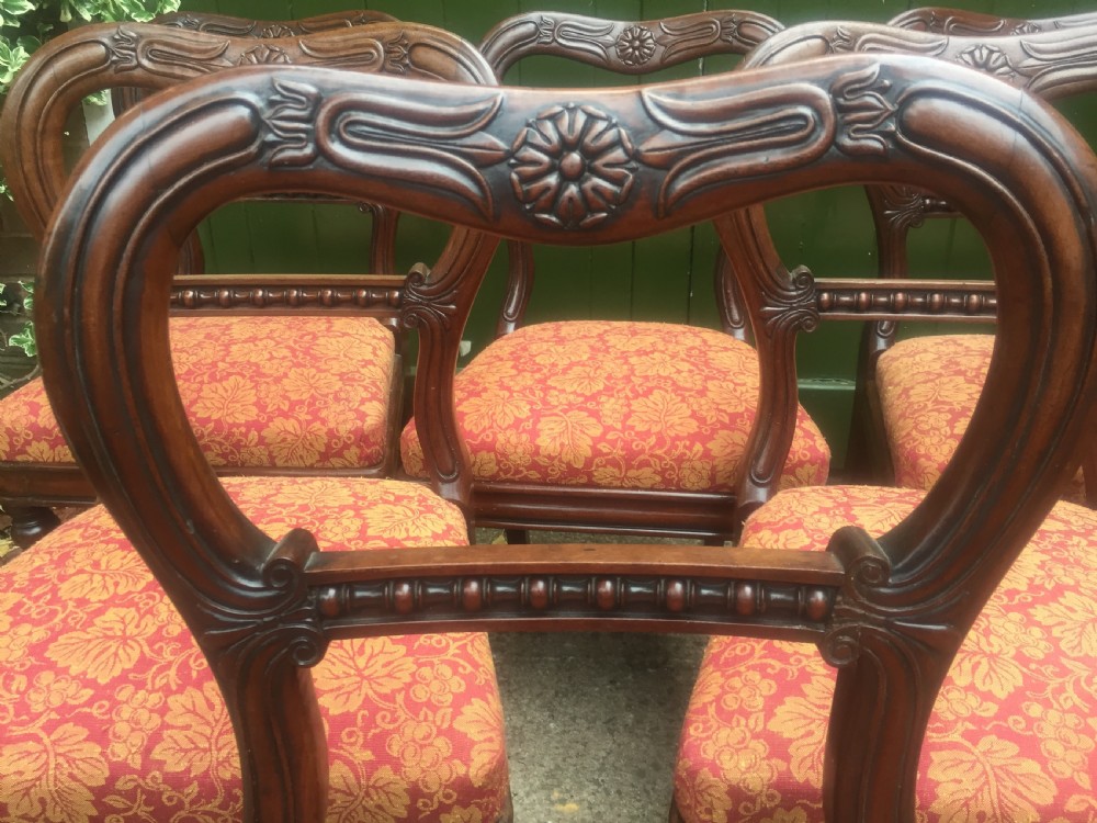 A set of six early nineteenth-century George IV mahogany dining chairs featuring carved balloon back frames, reeded legs, and red pattern upholstered seats. View VI