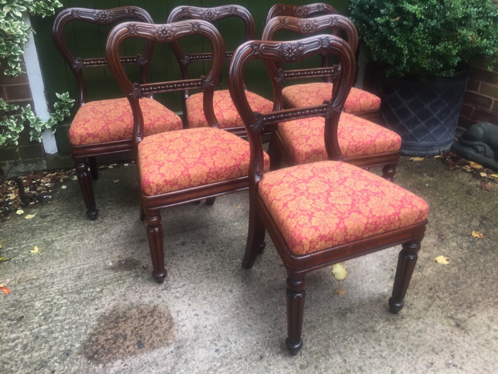 A set of six early nineteenth-century George IV mahogany dining chairs featuring carved balloon back frames, reeded legs, and red pattern upholstered seats. View VIII