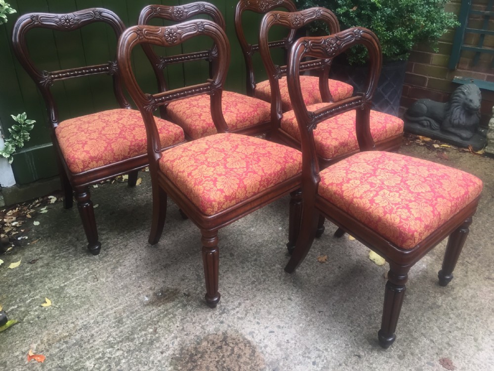 A set of six early nineteenth-century George IV mahogany dining chairs featuring carved balloon back frames, reeded legs, and red pattern upholstered seats. View IX