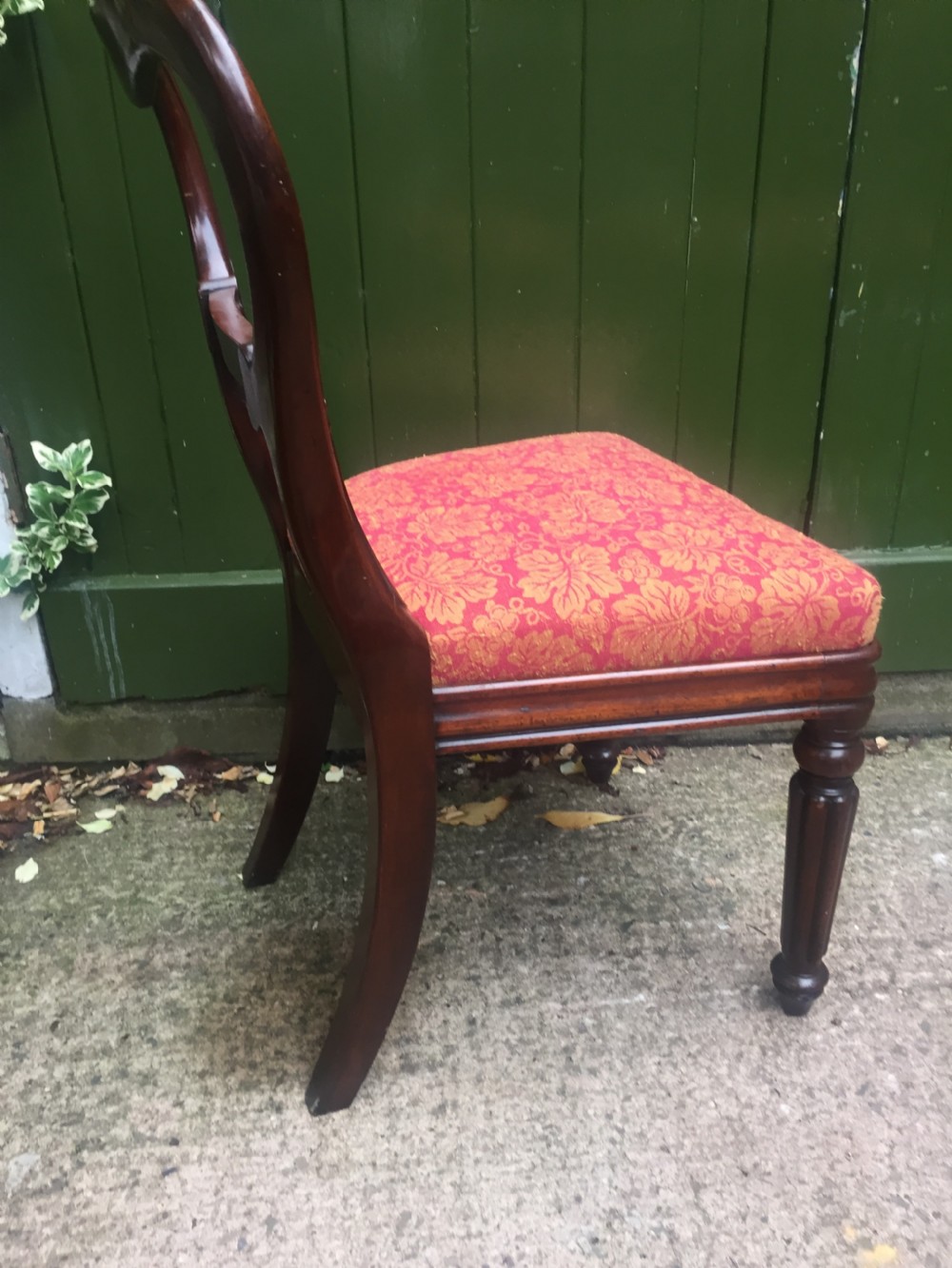 A set of six early nineteenth-century George IV mahogany dining chairs featuring carved balloon back frames, reeded legs, and red pattern upholstered seats. View XV