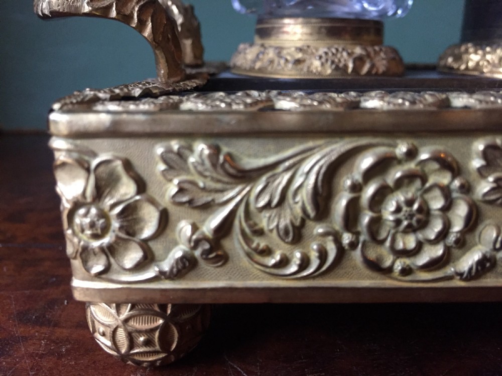 An early nineteenth-century French Empire style ormolu inkstand featuring two cut-crystal inkwells, a central holder, foliate handles, and a decorative gilt bronze tray. View X
