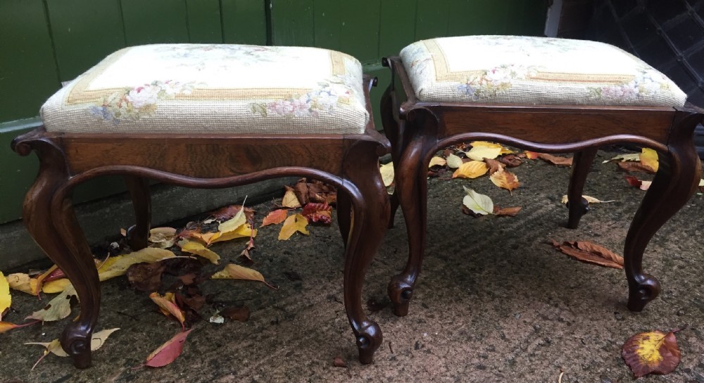 Pair of mid C19th Victorian period carved and figured rosewood-framed stools with needlework seats.
