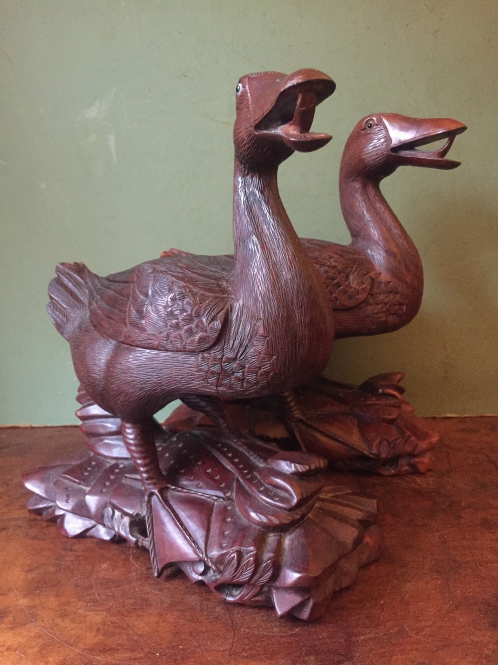 A pair of late nineteenth-century Chinese hardwood carved ducks with open beaks resting on sculpted bases.