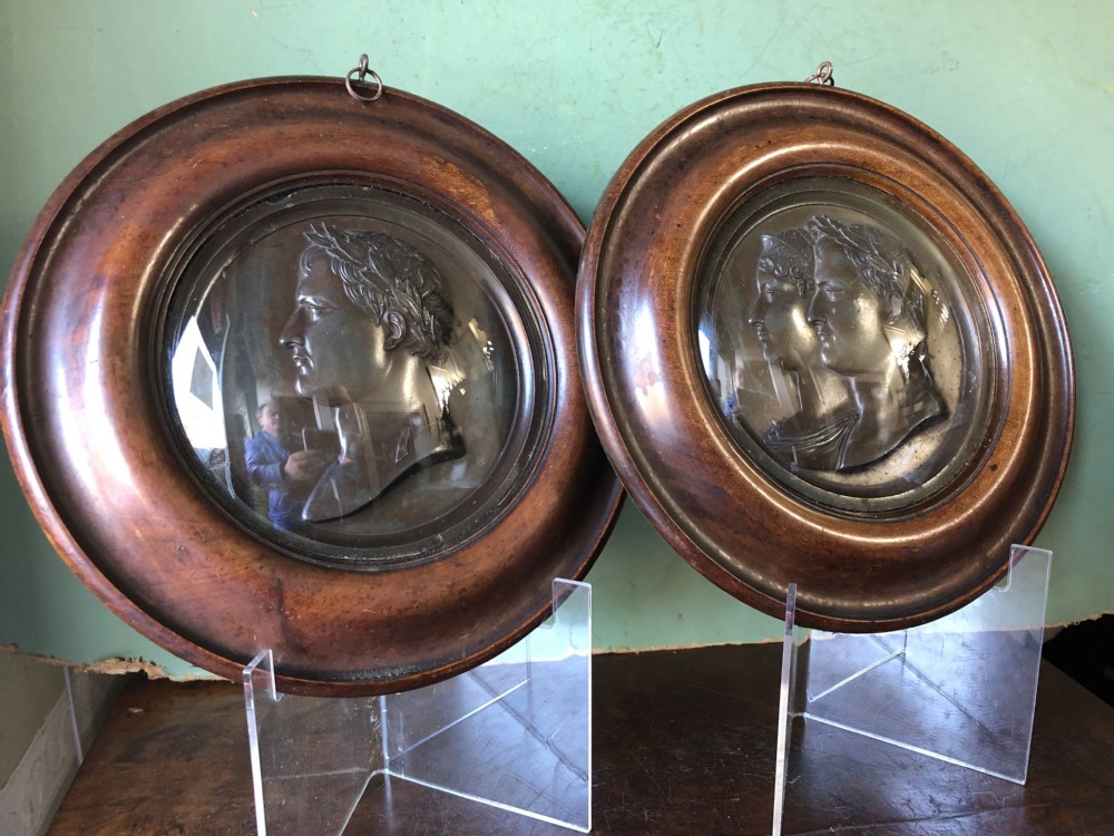 A pair of circular turned mahogany frames enclosing dark bronzed relief profile portraits of Napoleon and Marie-Louise under glass.
