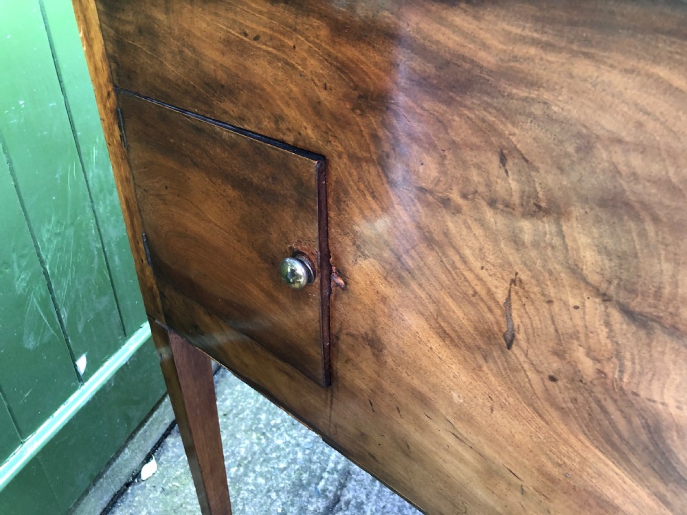 A late 18th-century George III mahogany sideboard featuring a serpentine front, floral marquetry inlay, tapering square legs with spade feet, and brass oval handles. View X