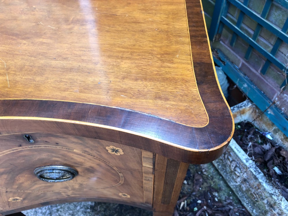 A late 18th-century George III mahogany sideboard featuring a serpentine front, floral marquetry inlay, tapering square legs with spade feet, and brass oval handles. View XIV