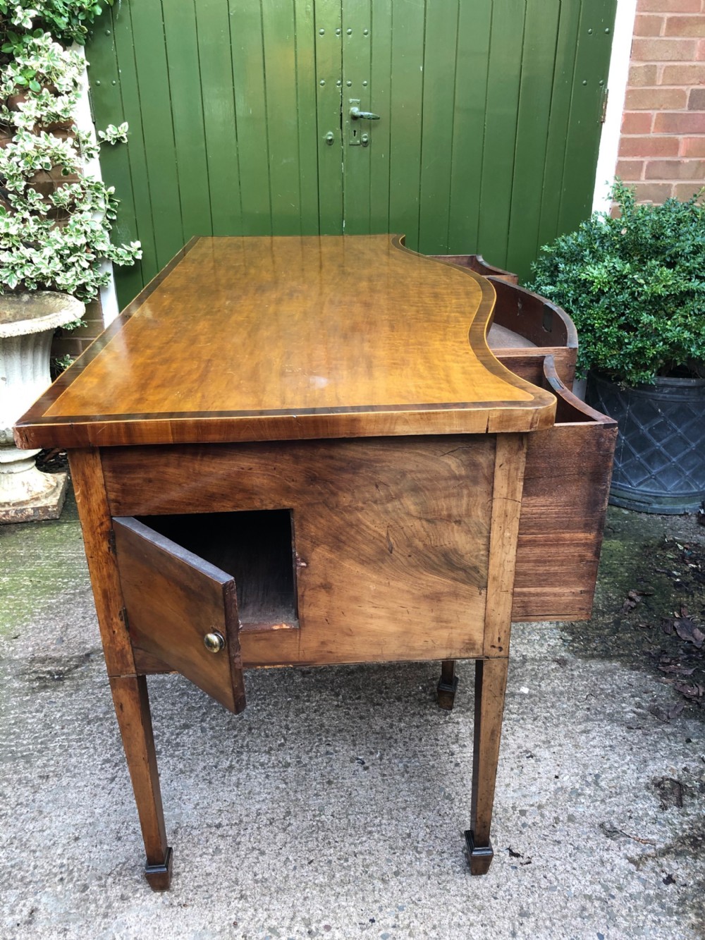 A late 18th-century George III mahogany sideboard featuring a serpentine front, floral marquetry inlay, tapering square legs with spade feet, and brass oval handles. View XVIII