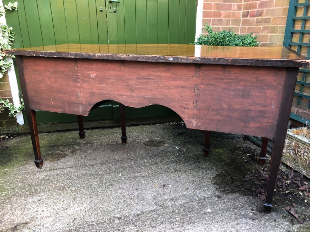 A late 18th-century George III mahogany sideboard featuring a serpentine front, floral marquetry inlay, tapering square legs with spade feet, and brass oval handles. View XXIII