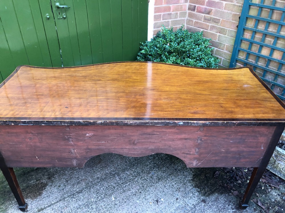 A late 18th-century George III mahogany sideboard featuring a serpentine front, floral marquetry inlay, tapering square legs with spade feet, and brass oval handles. View XXIV