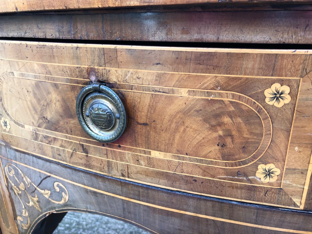A late 18th-century George III mahogany sideboard featuring a serpentine front, floral marquetry inlay, tapering square legs with spade feet, and brass oval handles. View XXVI