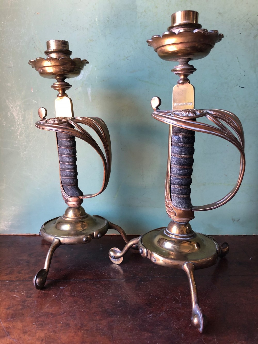 Pair of C19th Victorian period gilded and lacquered brass military design candlesticks with sword-hilt bodies .