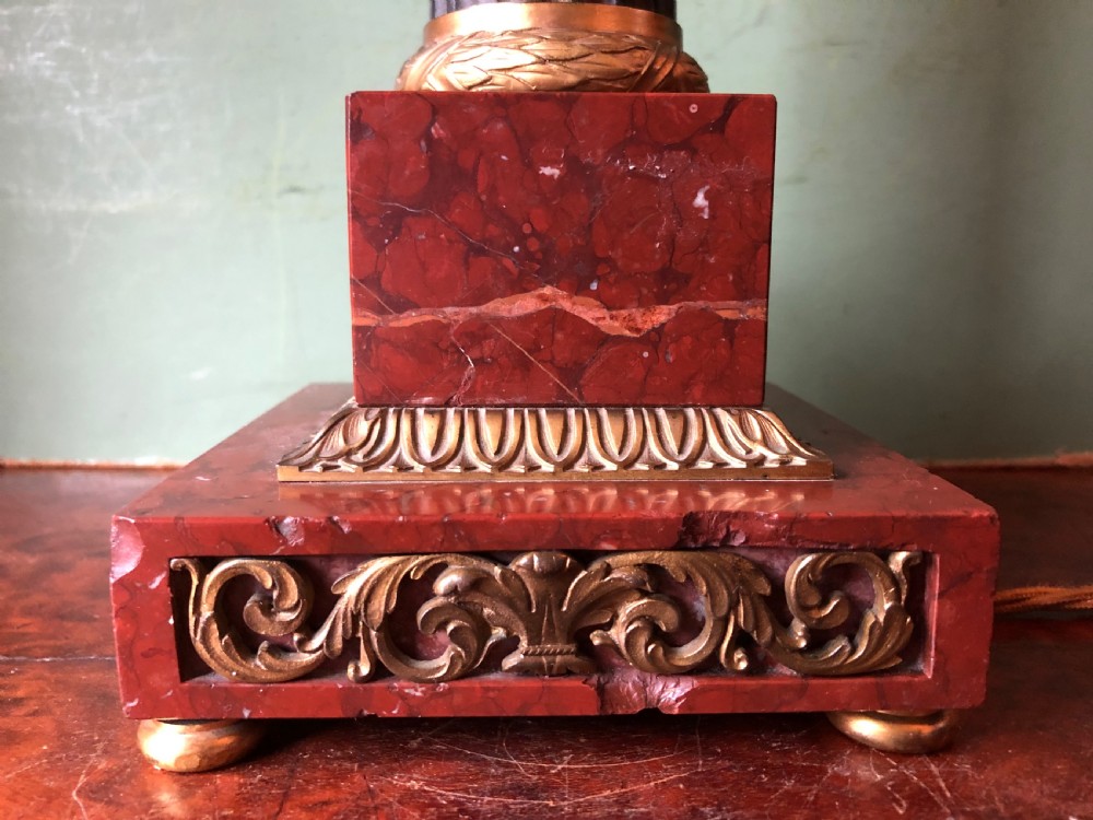 Late 19th-century French Empire style table lamp featuring a dark patinated bronze fluted column on a red marble base with gilded ormolu accents. View X