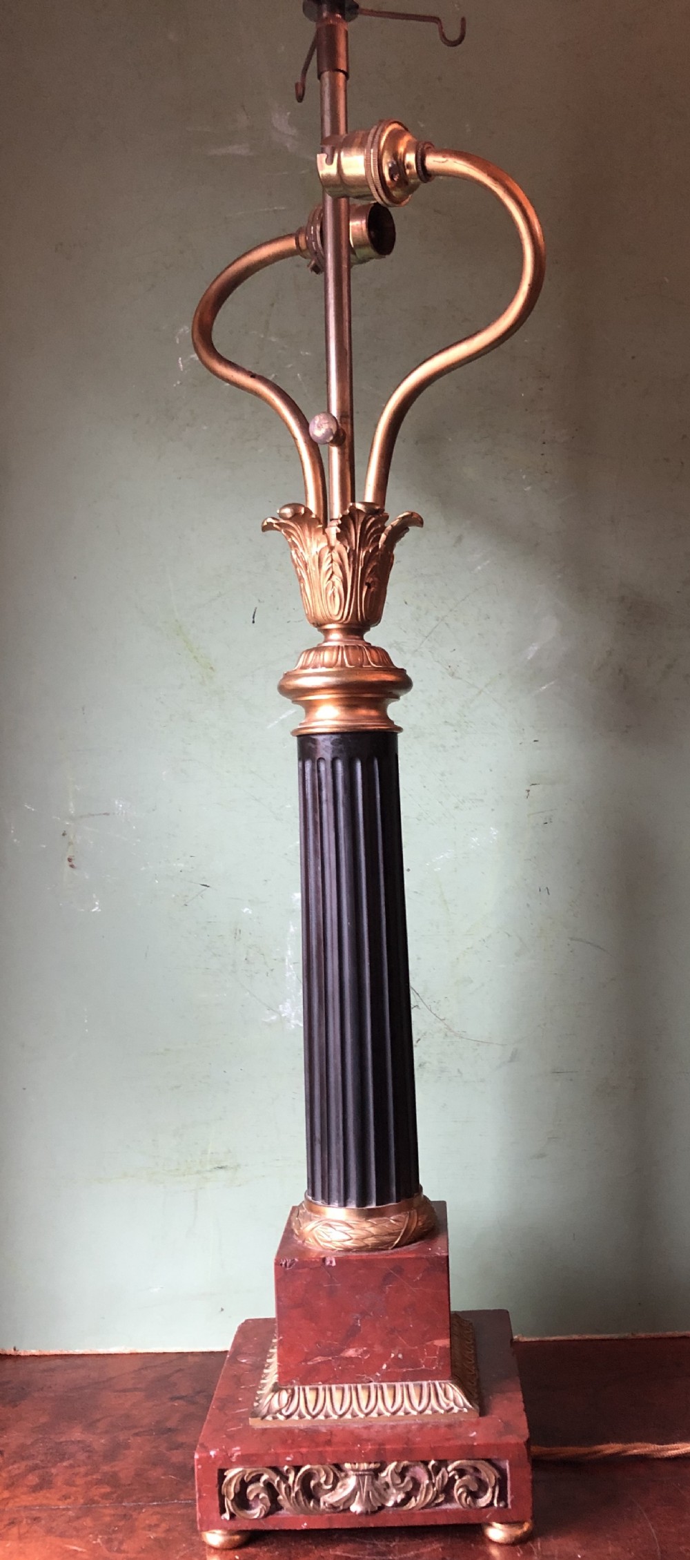 Late 19th-century French Empire style table lamp featuring a dark patinated bronze fluted column on a red marble base with gilded ormolu accents.