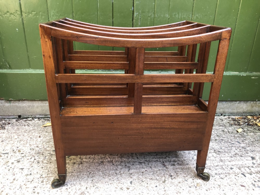 A late George III mahogany canterbury featuring slatted dividers, a concave top crest rail, a single base drawer with brass knobs, and square legs ending in brass castors. View VII