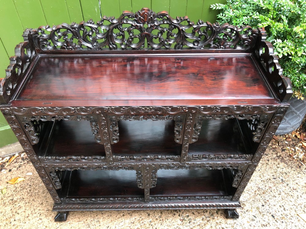 A dark rosewood late nineteenth-century Chinese display cabinet featuring intricate openwork carving throughout tiered open shelves and a crest rail. View III