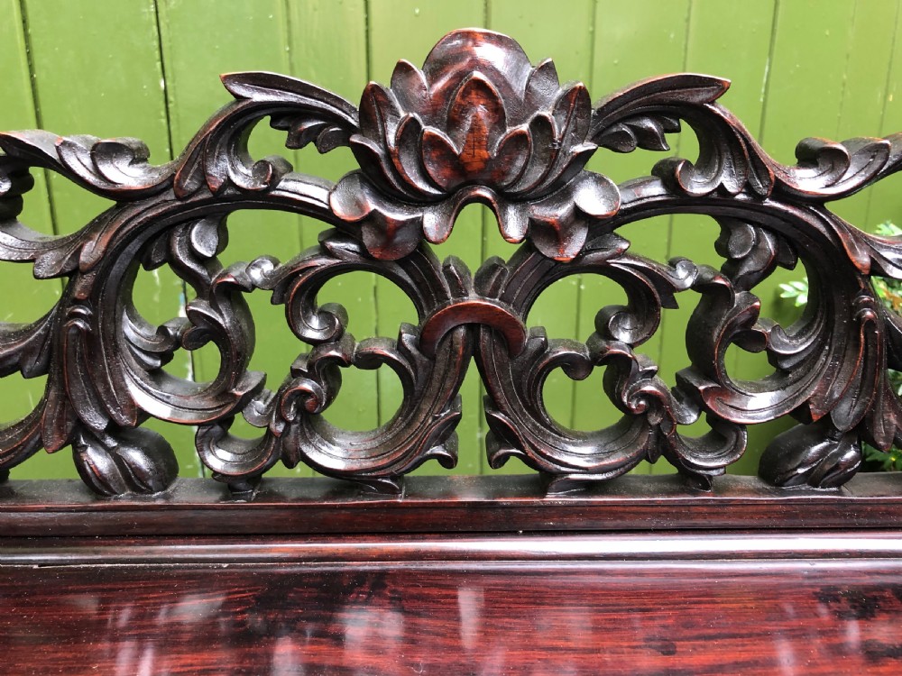 A dark rosewood late nineteenth-century Chinese display cabinet featuring intricate openwork carving throughout tiered open shelves and a crest rail. View V