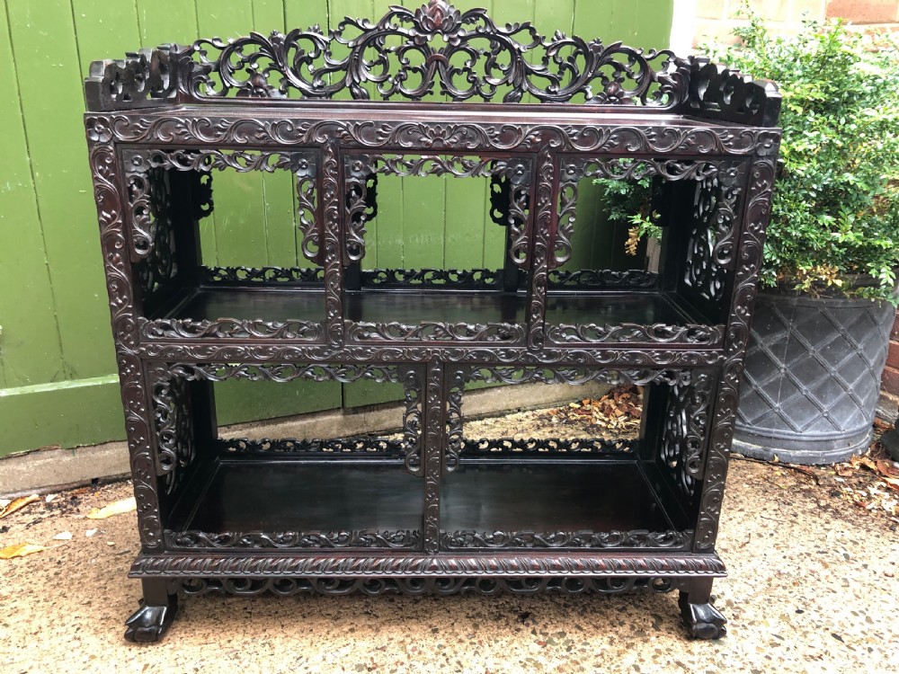 A dark rosewood late nineteenth-century Chinese display cabinet featuring intricate openwork carving throughout tiered open shelves and a crest rail. View VII