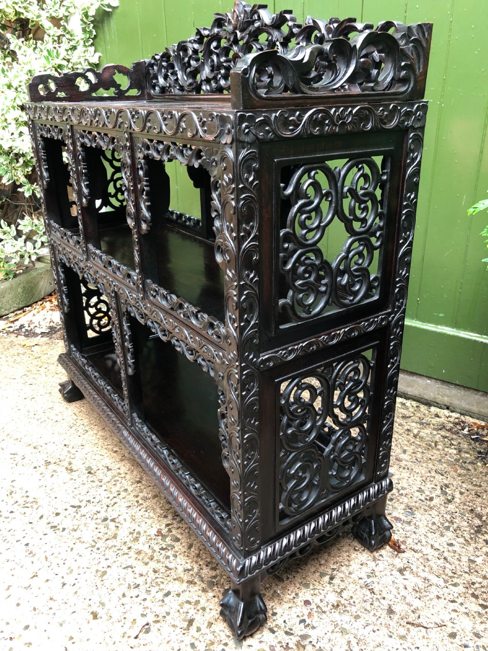 A dark rosewood late nineteenth-century Chinese display cabinet featuring intricate openwork carving throughout tiered open shelves and a crest rail. View IX