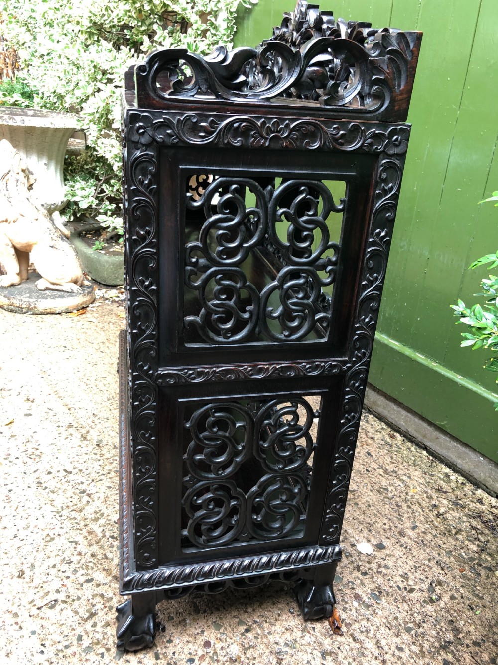 A dark rosewood late nineteenth-century Chinese display cabinet featuring intricate openwork carving throughout tiered open shelves and a crest rail. View X