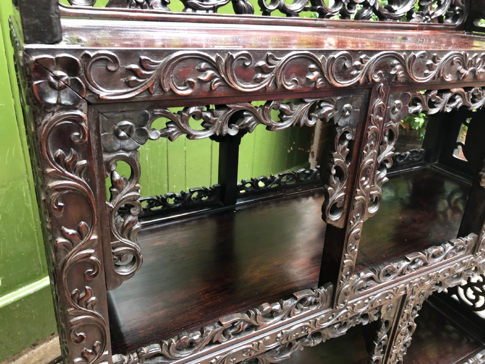 A dark rosewood late nineteenth-century Chinese display cabinet featuring intricate openwork carving throughout tiered open shelves and a crest rail. View XII