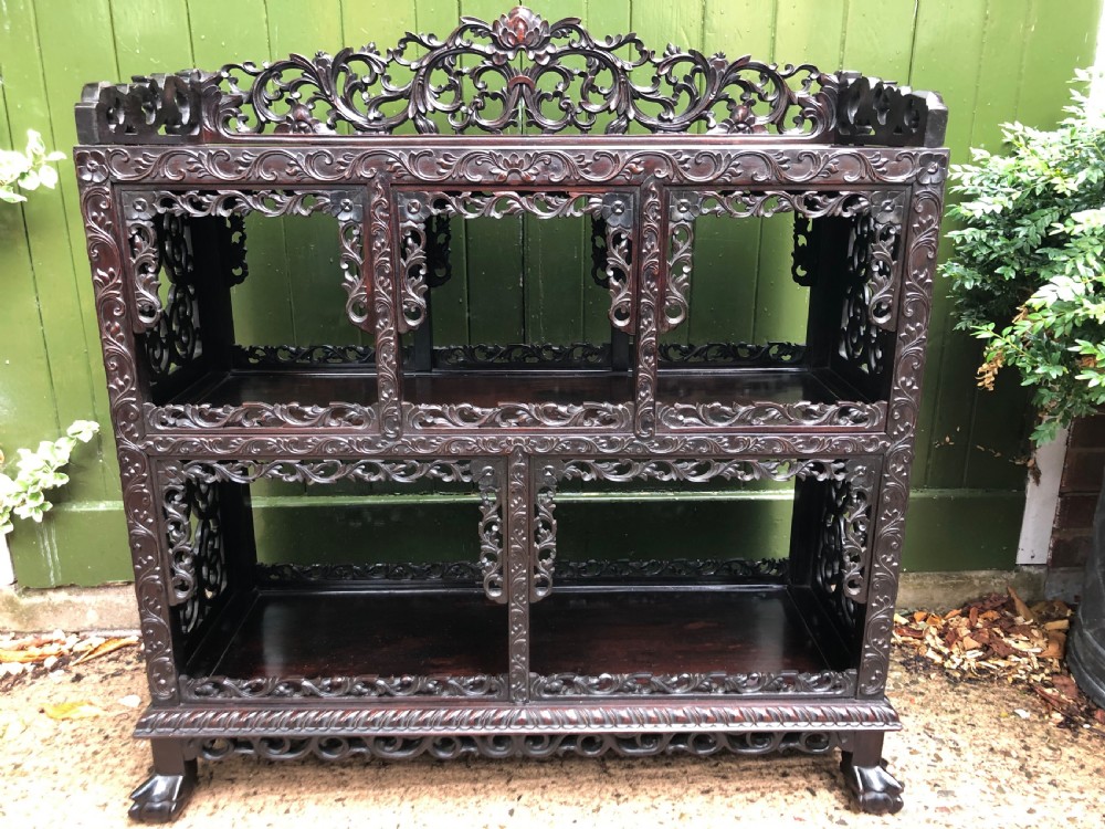A dark rosewood late nineteenth-century Chinese display cabinet featuring intricate openwork carving throughout tiered open shelves and a crest rail. View XVI