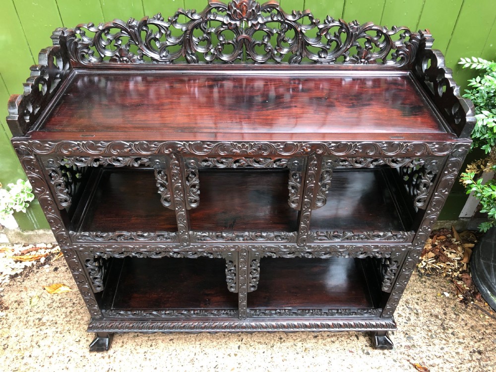 A dark rosewood late nineteenth-century Chinese display cabinet featuring intricate openwork carving throughout tiered open shelves and a crest rail. View XVIII