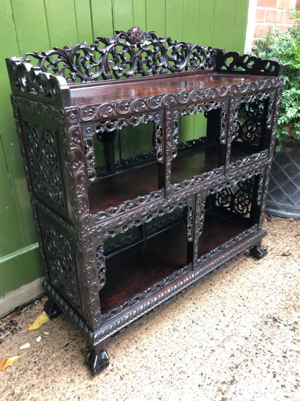A dark rosewood late nineteenth-century Chinese display cabinet featuring intricate openwork carving throughout tiered open shelves and a crest rail. View XX
