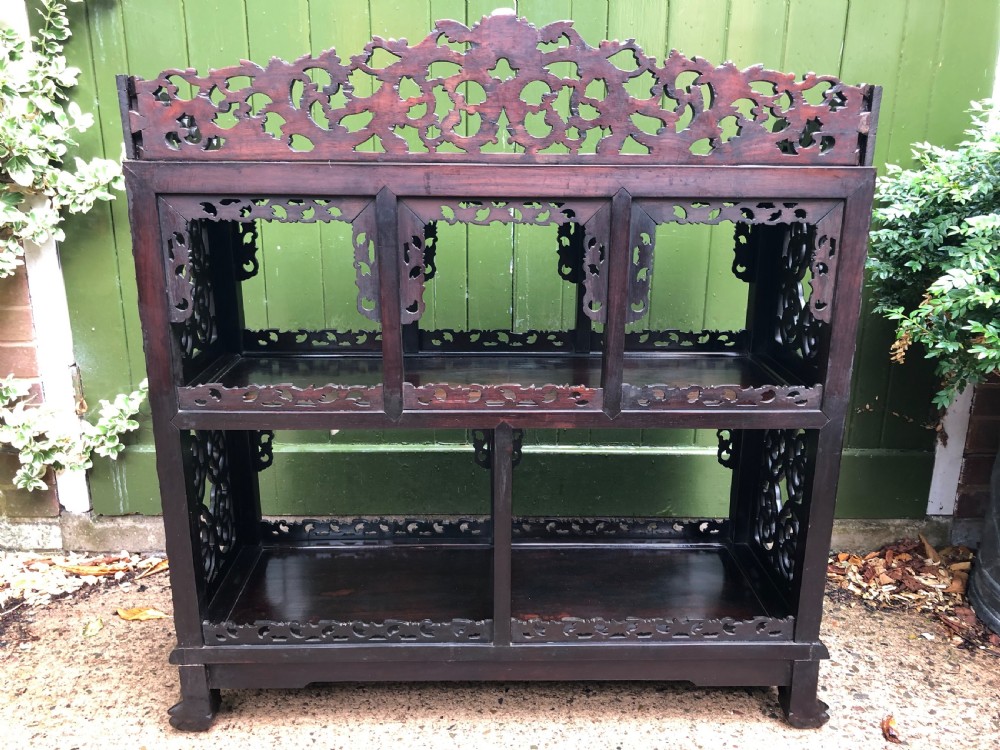 A dark rosewood late nineteenth-century Chinese display cabinet featuring intricate openwork carving throughout tiered open shelves and a crest rail. View XXIV