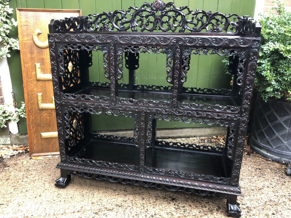 A dark rosewood late nineteenth-century Chinese display cabinet featuring intricate openwork carving throughout tiered open shelves and a crest rail. View II