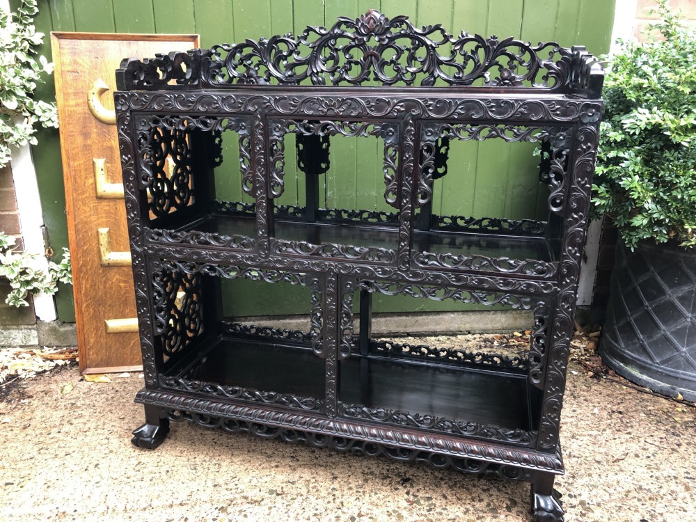 A dark rosewood late nineteenth-century Chinese display cabinet featuring intricate openwork carving throughout tiered open shelves and a crest rail. View XXI