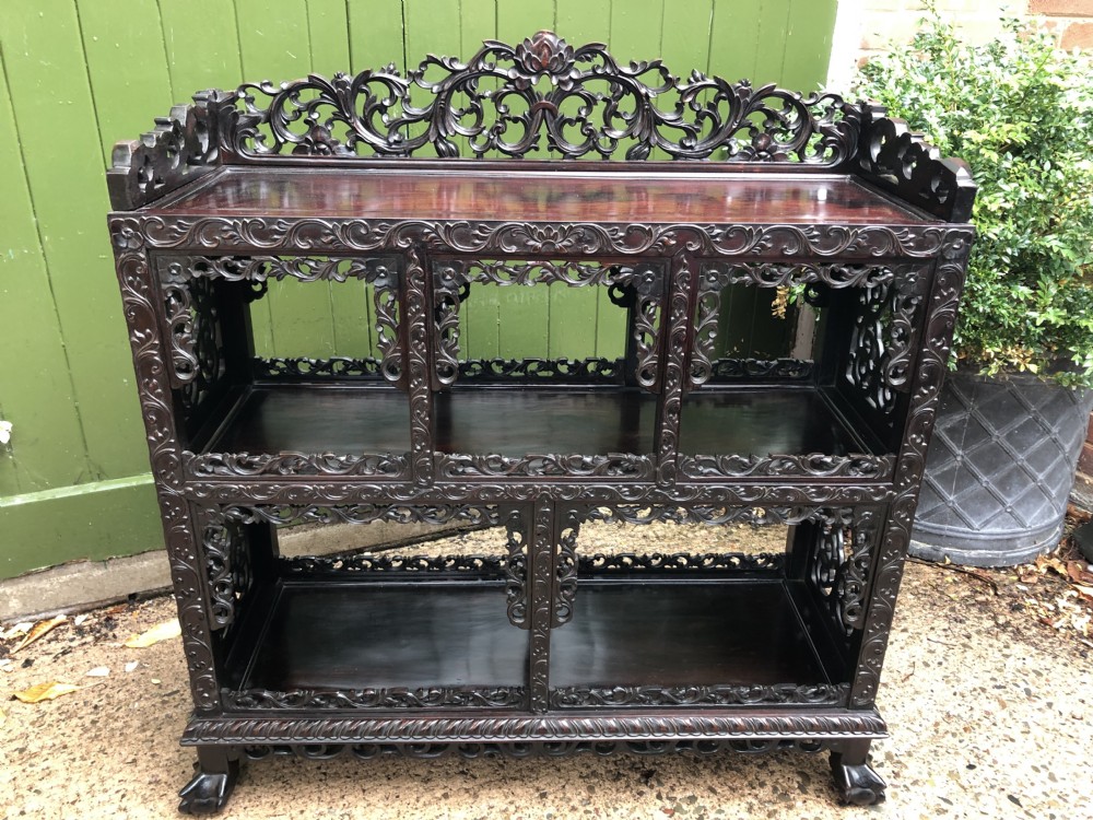 A dark rosewood late nineteenth-century Chinese display cabinet featuring intricate openwork carving throughout tiered open shelves and a crest rail. View XXV