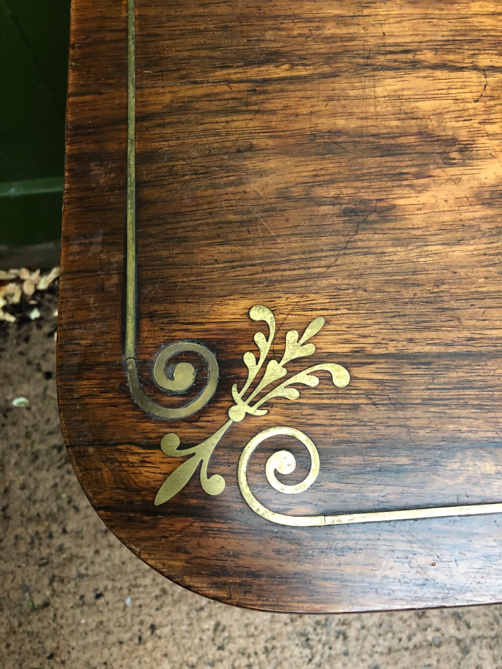 An early nineteenth-century Regency rosewood fold-over card table featuring decorative brass line inlay, a central pedestal, and splayed legs with brass claw feet. View V