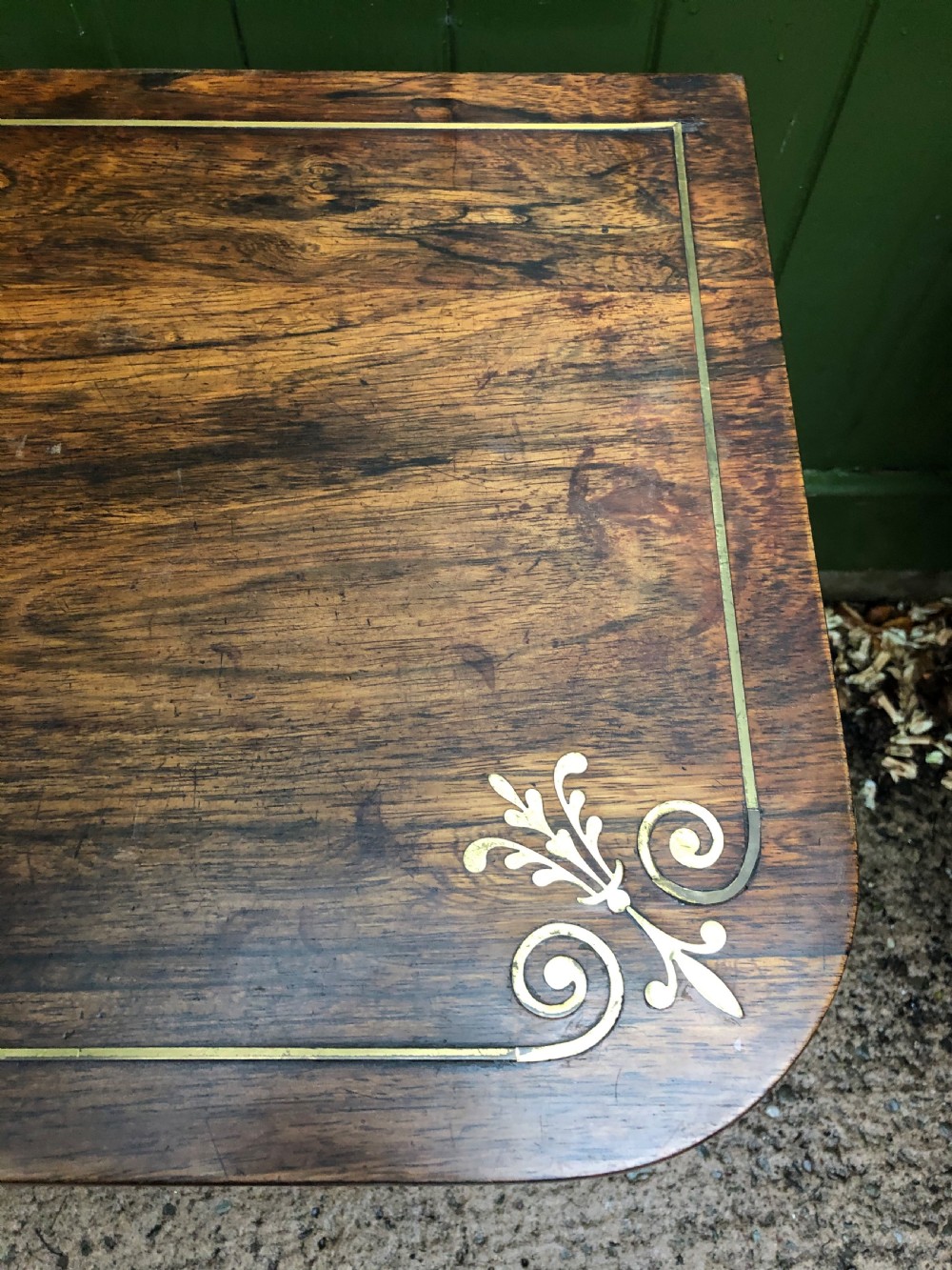 An early nineteenth-century Regency rosewood fold-over card table featuring decorative brass line inlay, a central pedestal, and splayed legs with brass claw feet. View VI