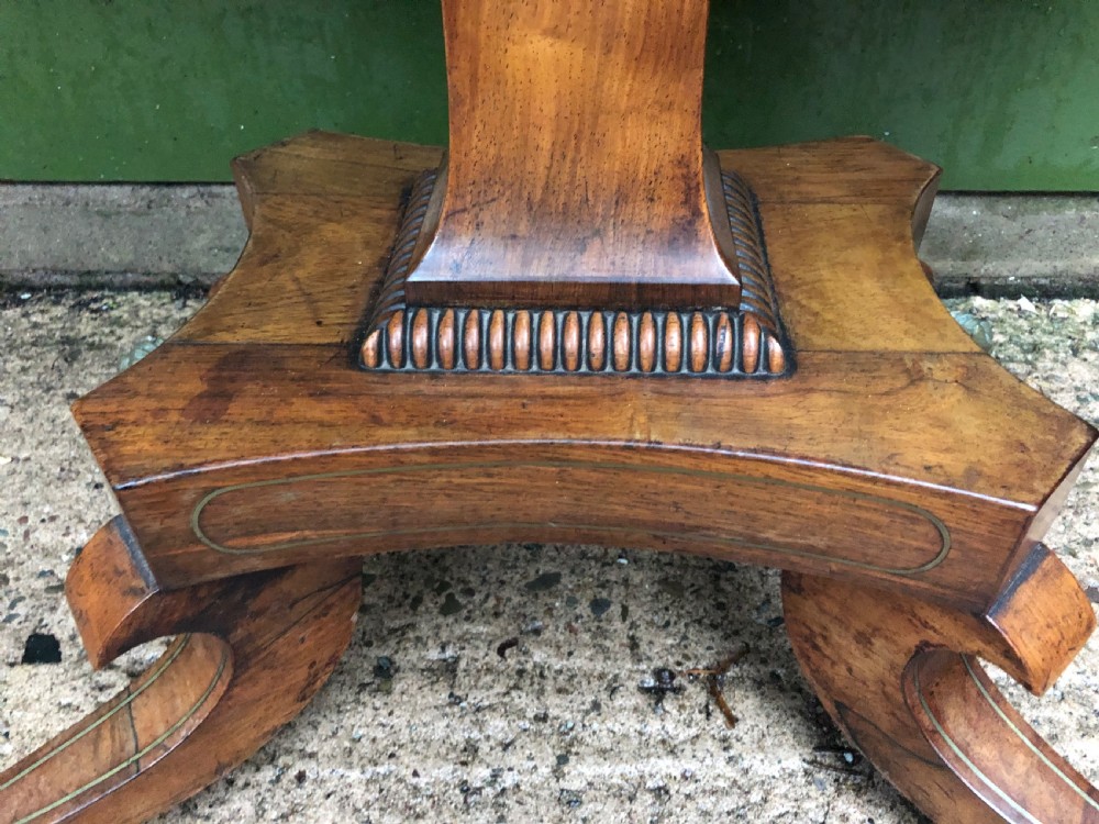An early nineteenth-century Regency rosewood fold-over card table featuring decorative brass line inlay, a central pedestal, and splayed legs with brass claw feet. View IX