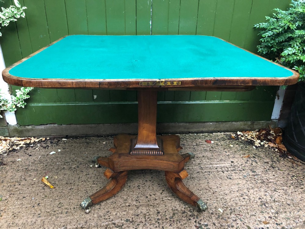 An early nineteenth-century Regency rosewood fold-over card table featuring decorative brass line inlay, a central pedestal, and splayed legs with brass claw feet. View XI