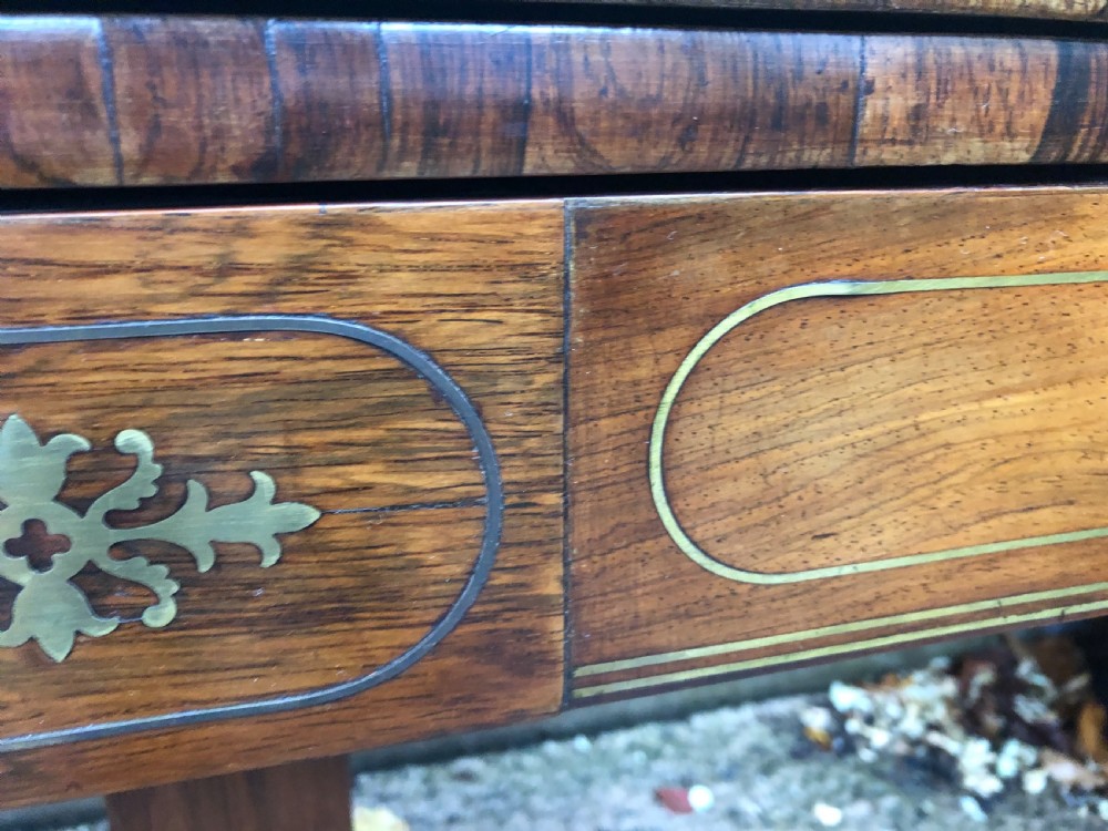 An early nineteenth-century Regency rosewood fold-over card table featuring decorative brass line inlay, a central pedestal, and splayed legs with brass claw feet. View XIII