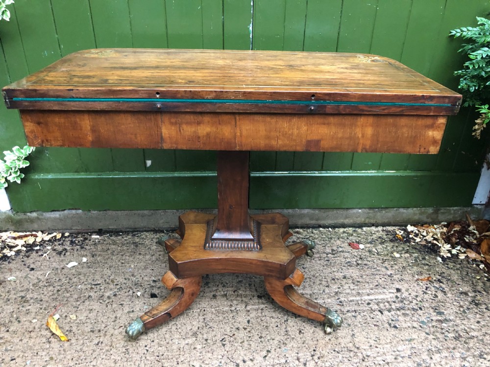 An early nineteenth-century Regency rosewood fold-over card table featuring decorative brass line inlay, a central pedestal, and splayed legs with brass claw feet. View XV