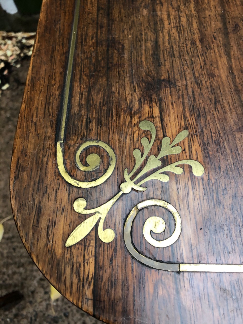 An early nineteenth-century Regency rosewood fold-over card table featuring decorative brass line inlay, a central pedestal, and splayed legs with brass claw feet. View XX