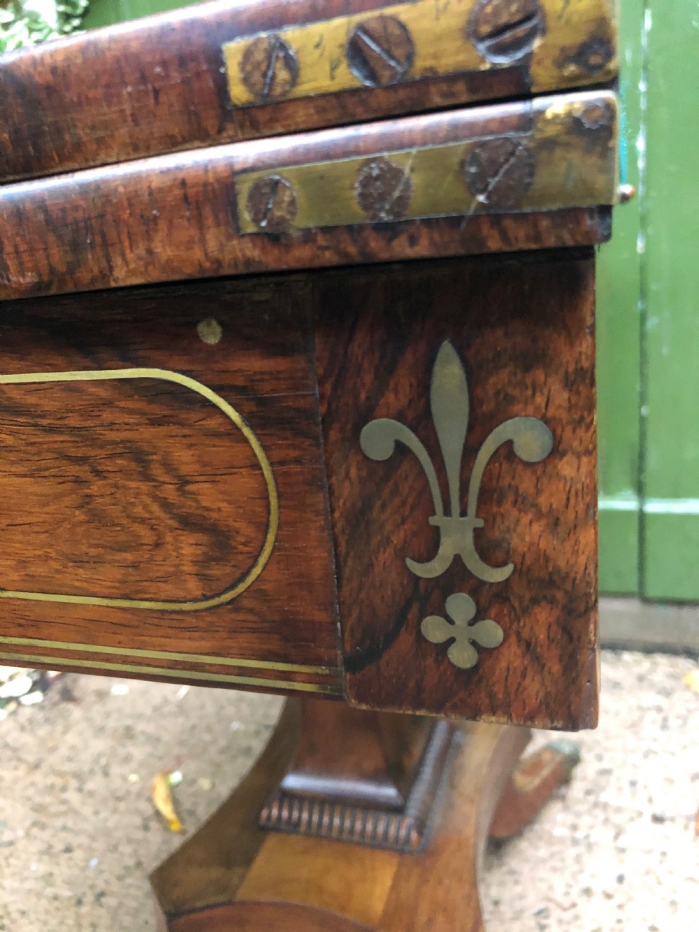 An early nineteenth-century Regency rosewood fold-over card table featuring decorative brass line inlay, a central pedestal, and splayed legs with brass claw feet. View XXI