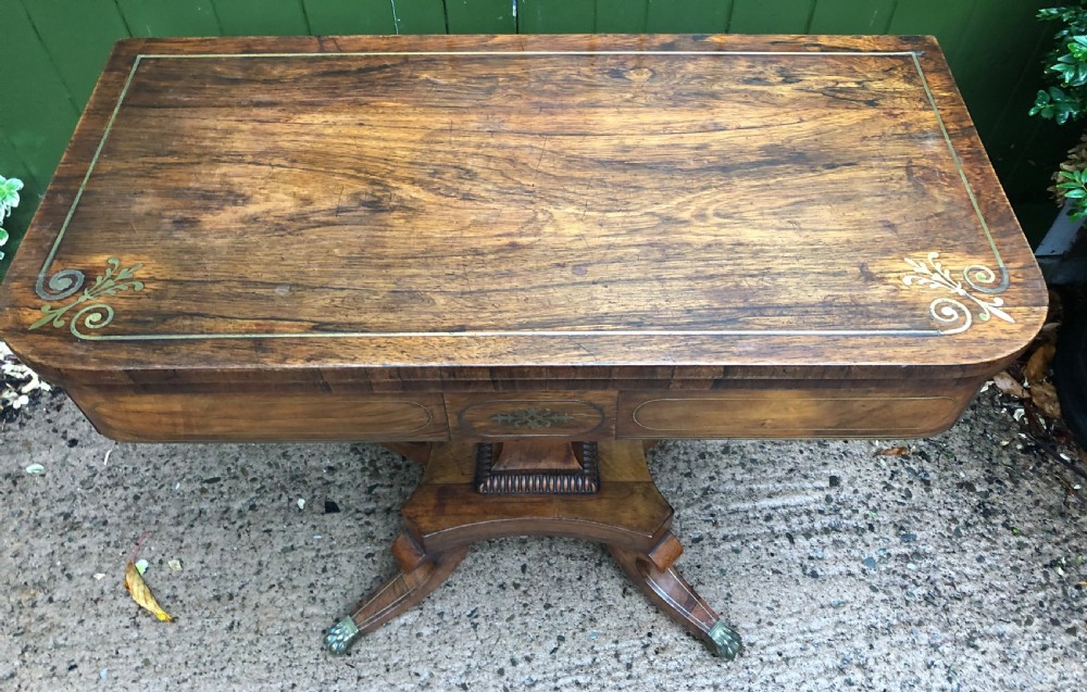 An early nineteenth-century Regency rosewood fold-over card table featuring decorative brass line inlay, a central pedestal, and splayed legs with brass claw feet. View XXIII