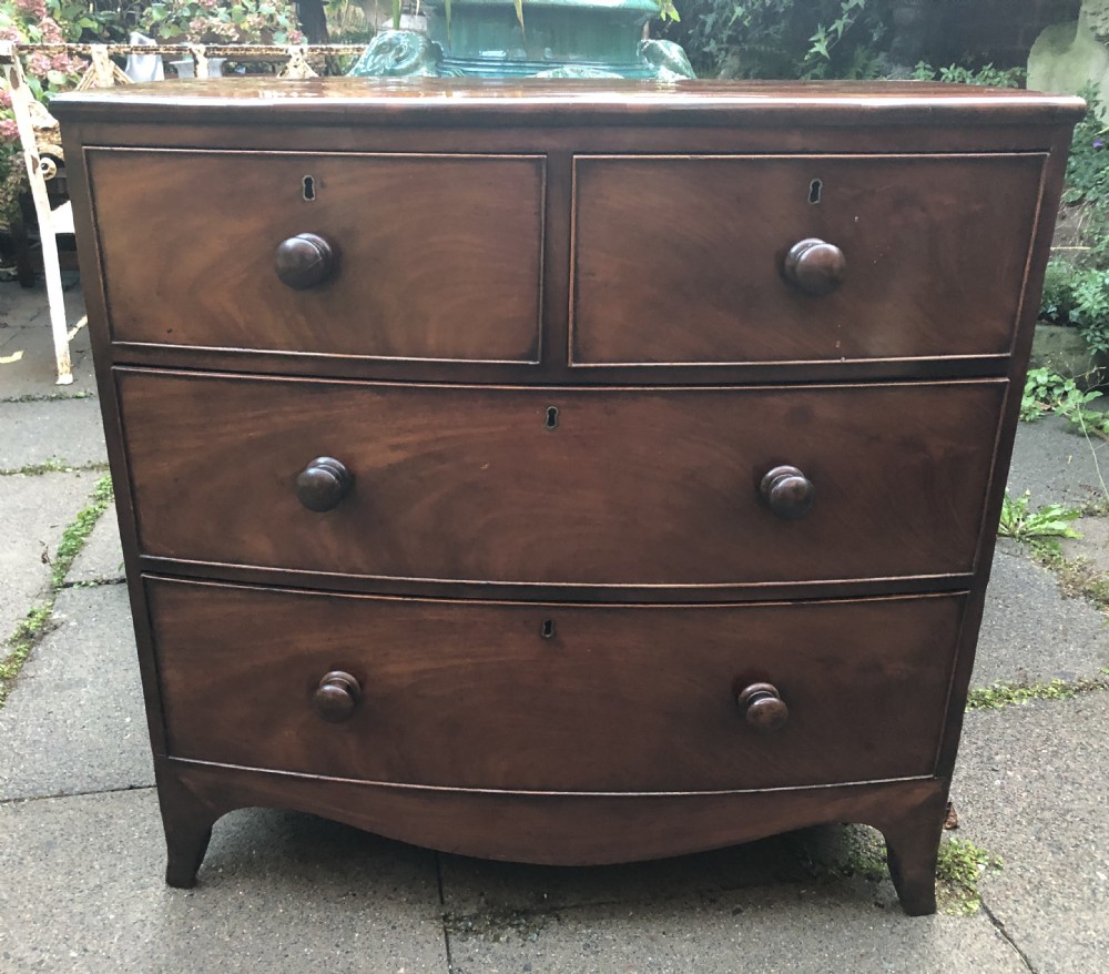 An early nineteenth-century George III mahogany bowfront chest of drawers featuring two short over two long drawers with turned knobs and splayed bracket feet.
