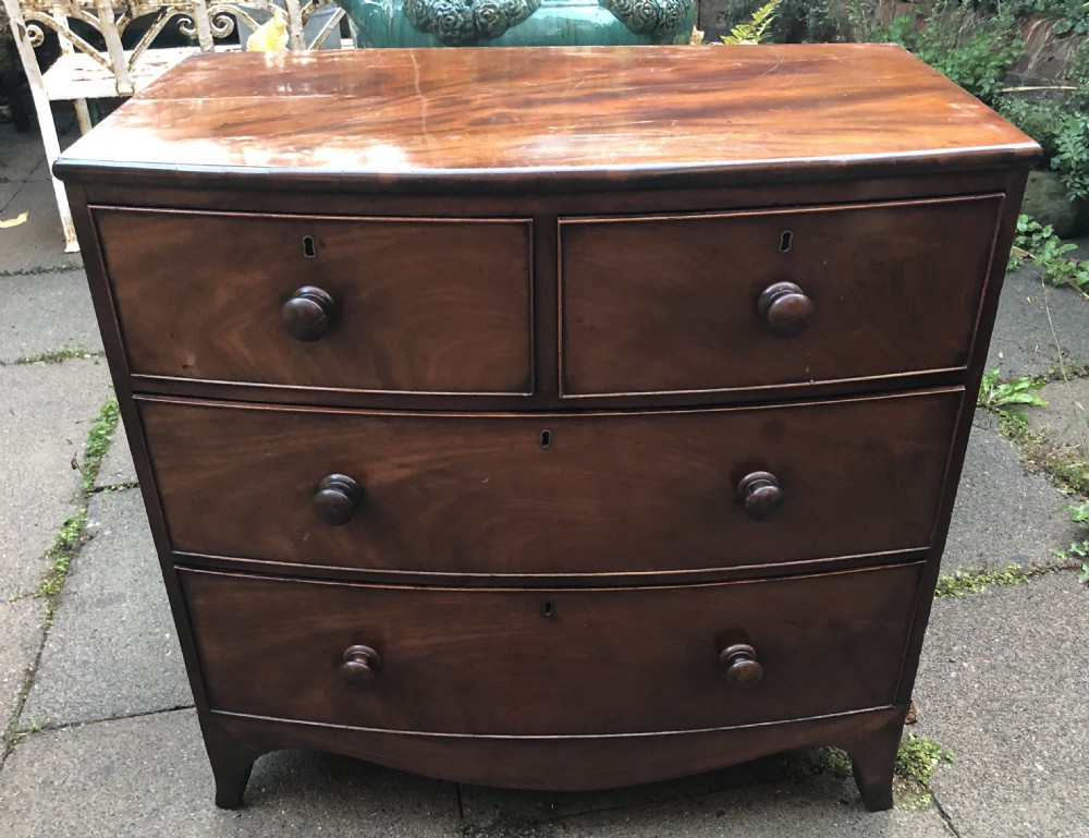 An early nineteenth-century George III mahogany bowfront chest of drawers featuring two short over two long drawers with turned knobs and splayed bracket feet. View II