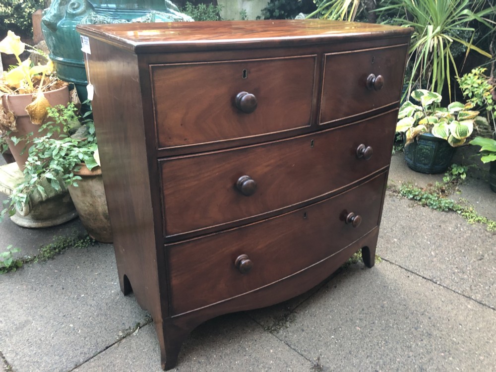 An early nineteenth-century George III mahogany bowfront chest of drawers featuring two short over two long drawers with turned knobs and splayed bracket feet. View III