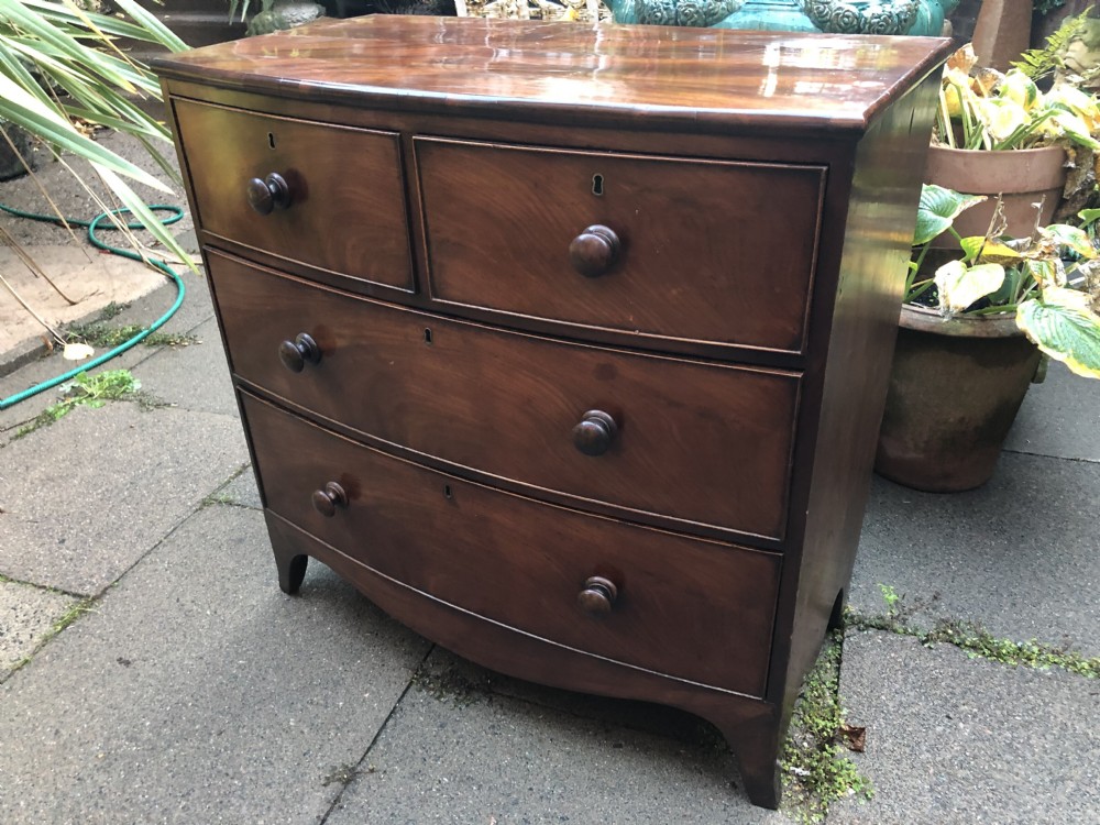 An early nineteenth-century George III mahogany bowfront chest of drawers featuring two short over two long drawers with turned knobs and splayed bracket feet. View V