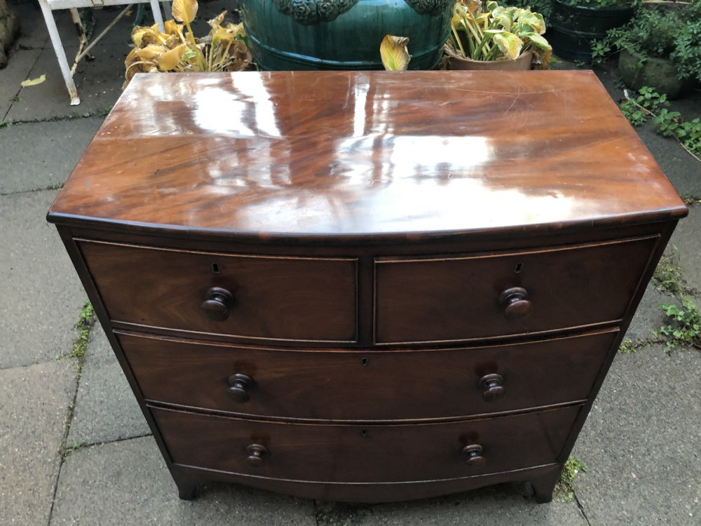 An early nineteenth-century George III mahogany bowfront chest of drawers featuring two short over two long drawers with turned knobs and splayed bracket feet. View VI
