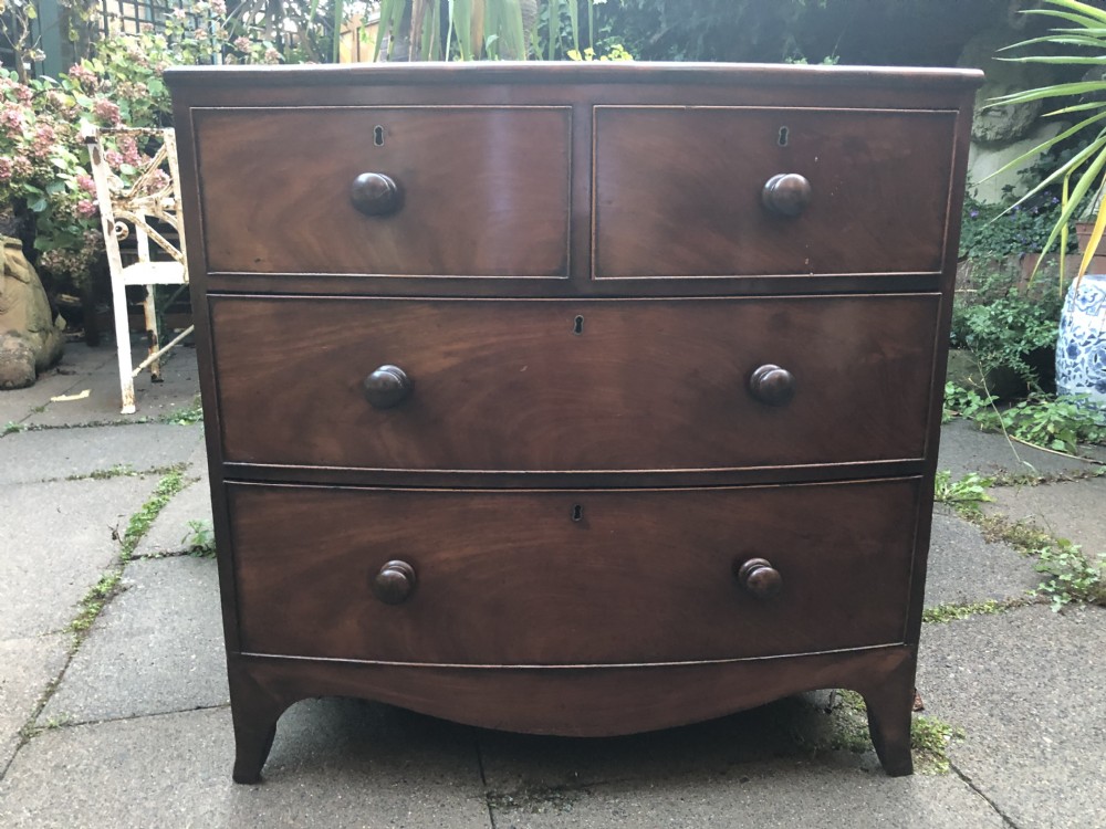 An early nineteenth-century George III mahogany bowfront chest of drawers featuring two short over two long drawers with turned knobs and splayed bracket feet. View VII