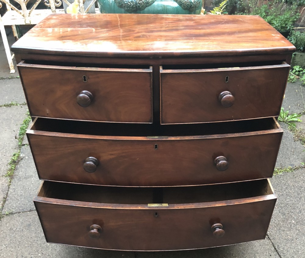 An early nineteenth-century George III mahogany bowfront chest of drawers featuring two short over two long drawers with turned knobs and splayed bracket feet. View XI