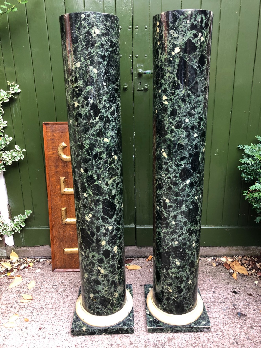 A pair of tall mid-19th century cylindrical wooden display columns painted in a green and black faux verde antico marble finish with square bases. View II