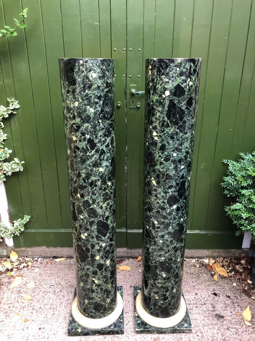A pair of tall mid-19th century cylindrical wooden display columns painted in a green and black faux verde antico marble finish with square bases. View V
